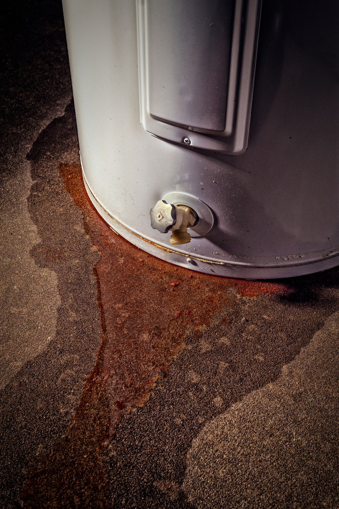 A domestic water heater leaking with signs of rust and iron in the water